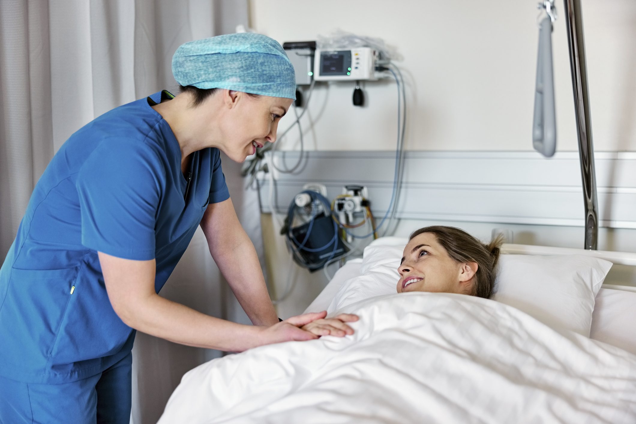Nurse comforting patient in hospital bed