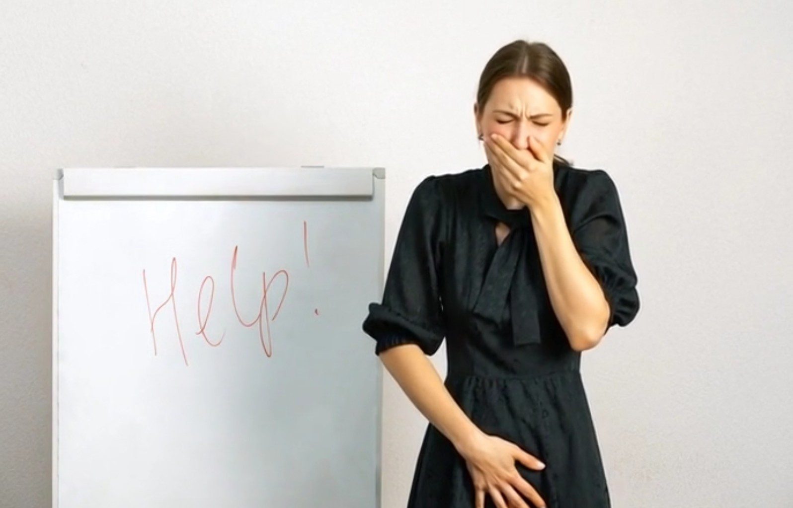 A woman looks distressed near a whiteboard with 'Help?' written on it.