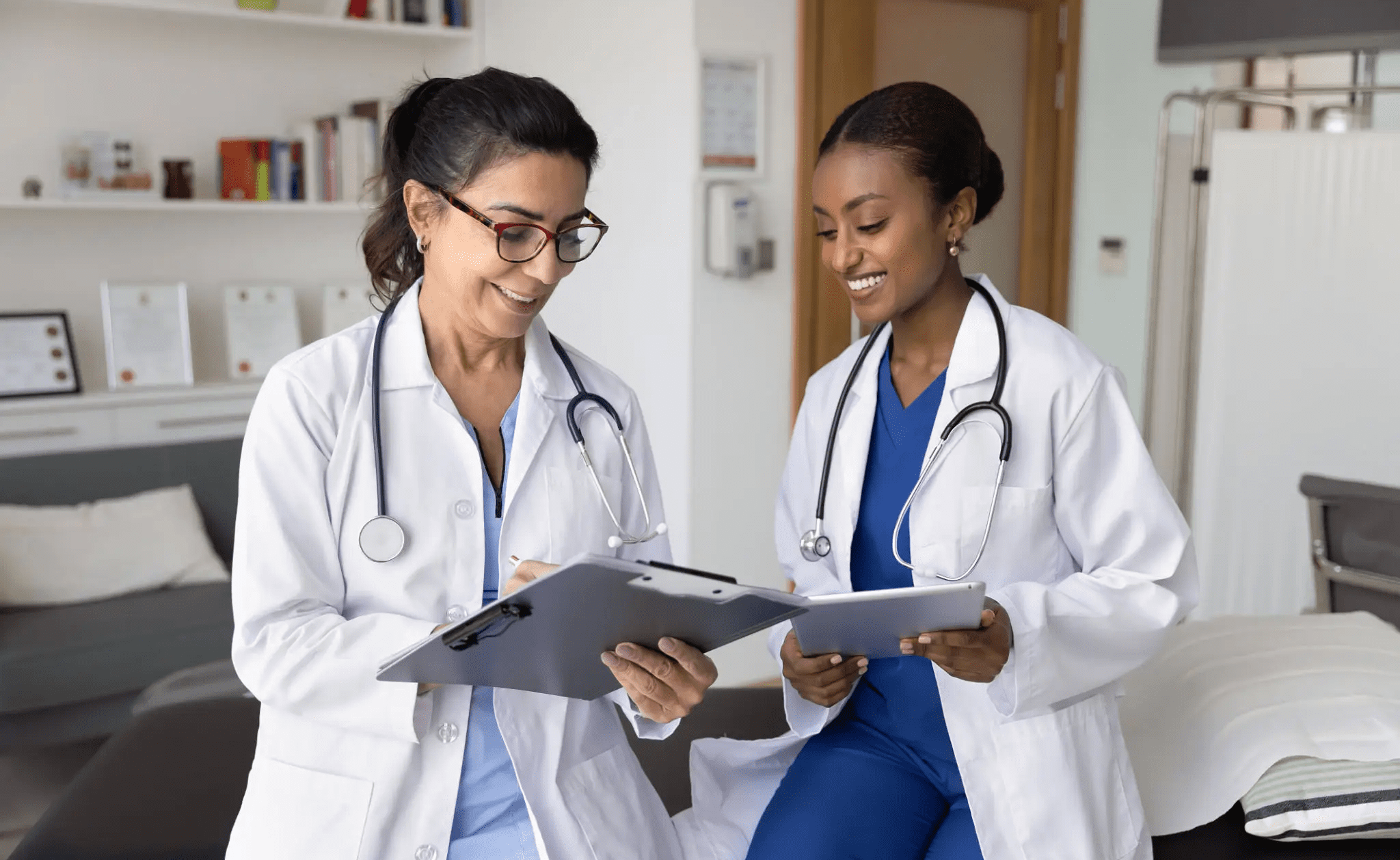 Two female doctors reviewing patient charts together in a medical office.